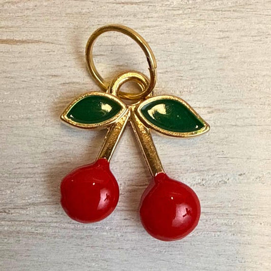 Red enamel cherry charm with green leaves and gold accents