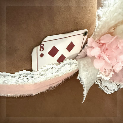 Beautified close-up of the exact eight of diamonds playing card hat add-on with brass eyelet and handmade floral styling