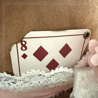 Beautified detail view of the exact distressed eight of diamonds card tucked behind lace and ribbon on a western hat
